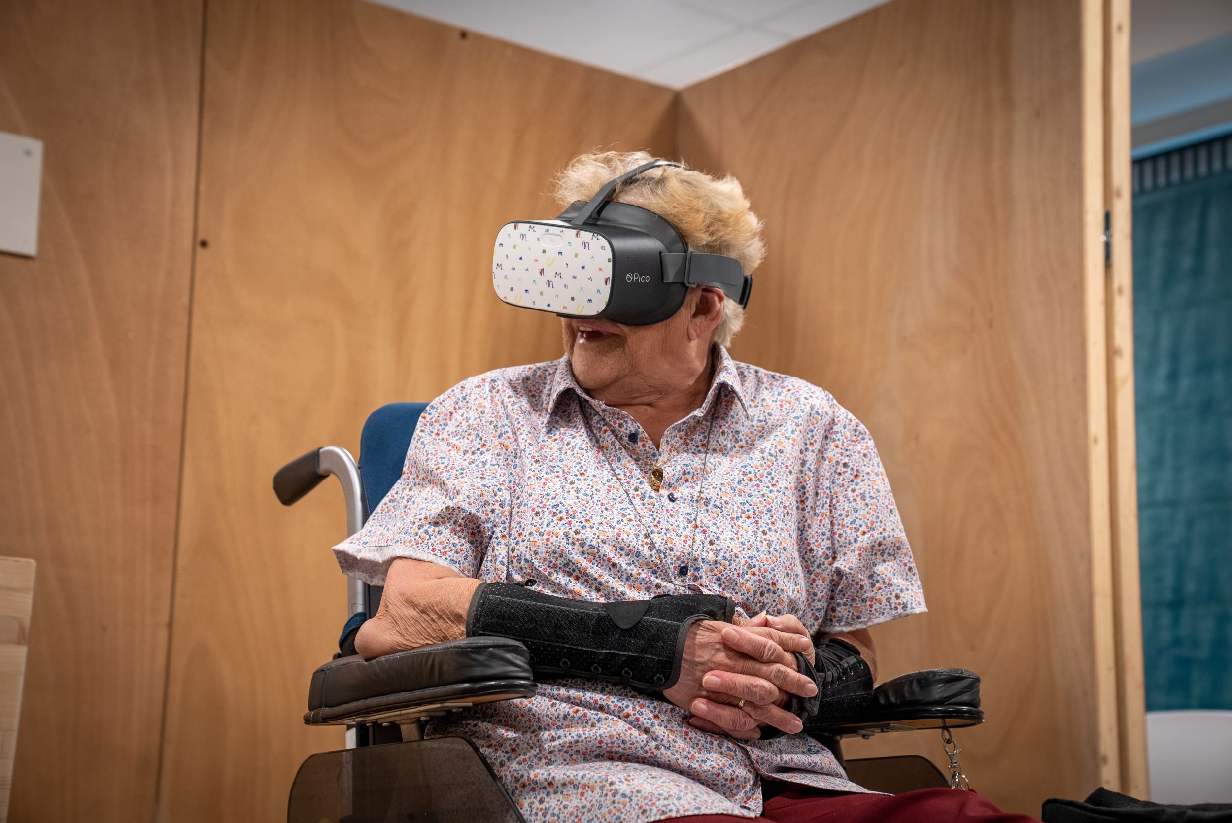 oud persoon met witte haren in een rolstoel met een VR bril op