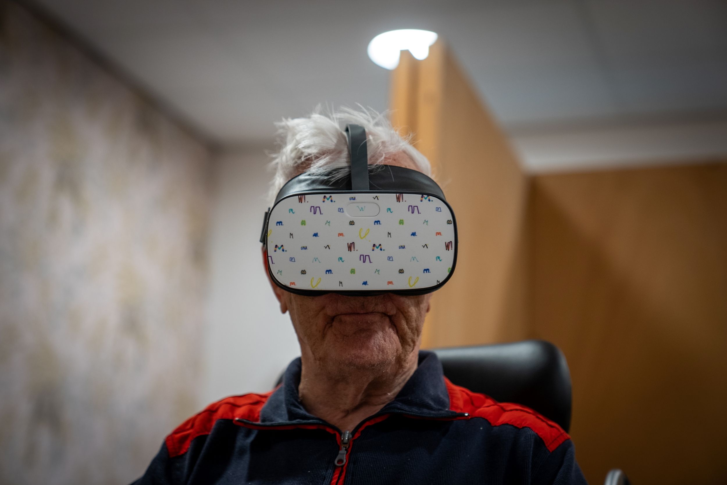 oude witte man met grijs haar en een VR bril op zijn ogen die de camera inkijkt