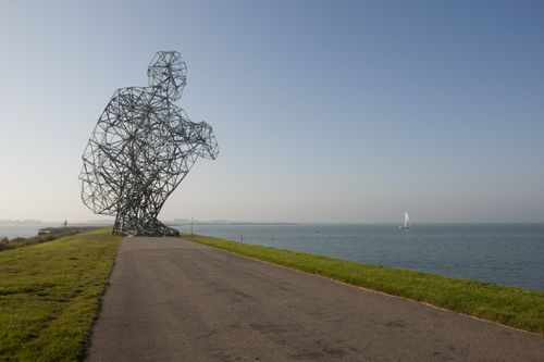 kunstwerk van een hurkende man aan het water